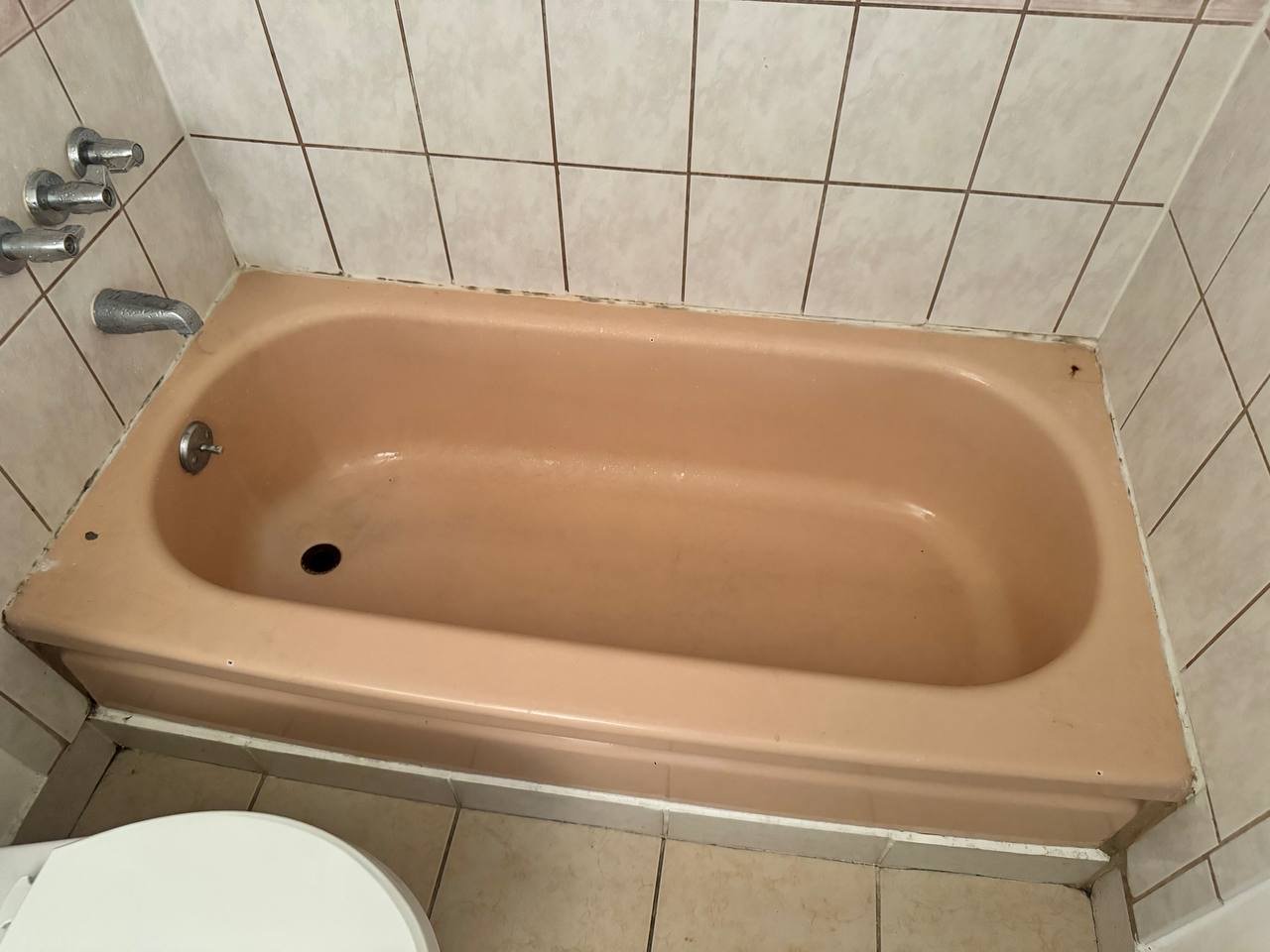 Outdated beige bathtub with worn finish requiring restoration and color update