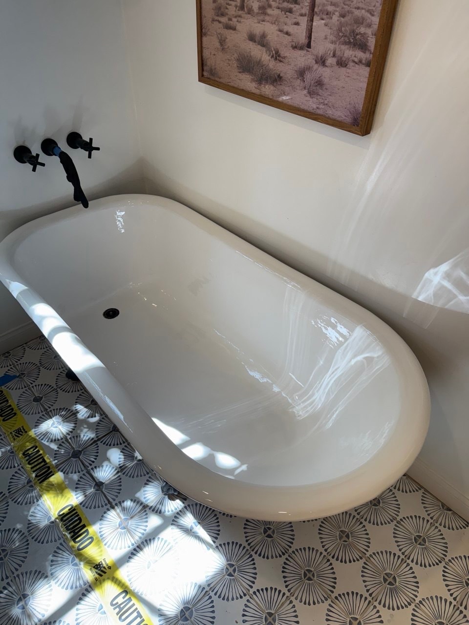 Refinished white freestanding bathtub with protective tape around the work area