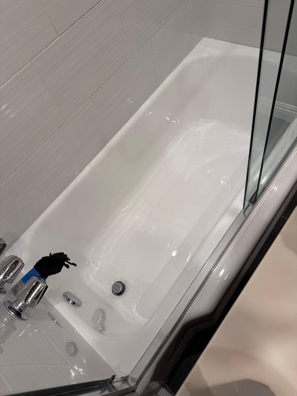 Refinished white bathtub viewed beside the Manhattan Beach glass enclosure