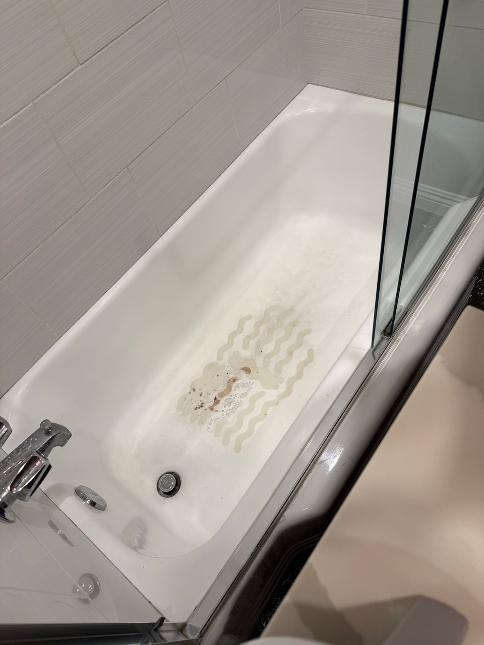 Discolored bathtub interior before refinishing, viewed from the faucet end