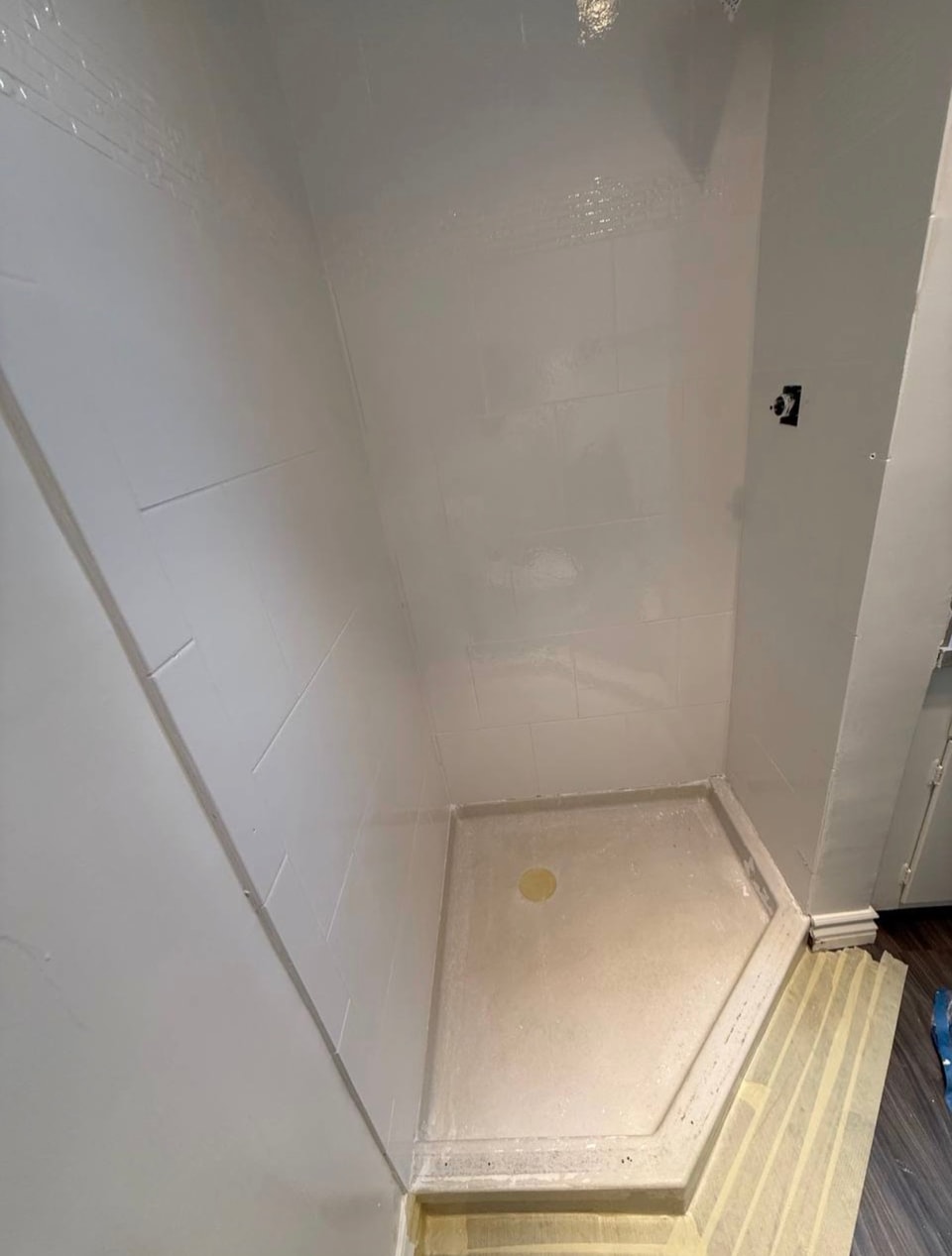 Shower wall tile refinished in white above the existing shower pan