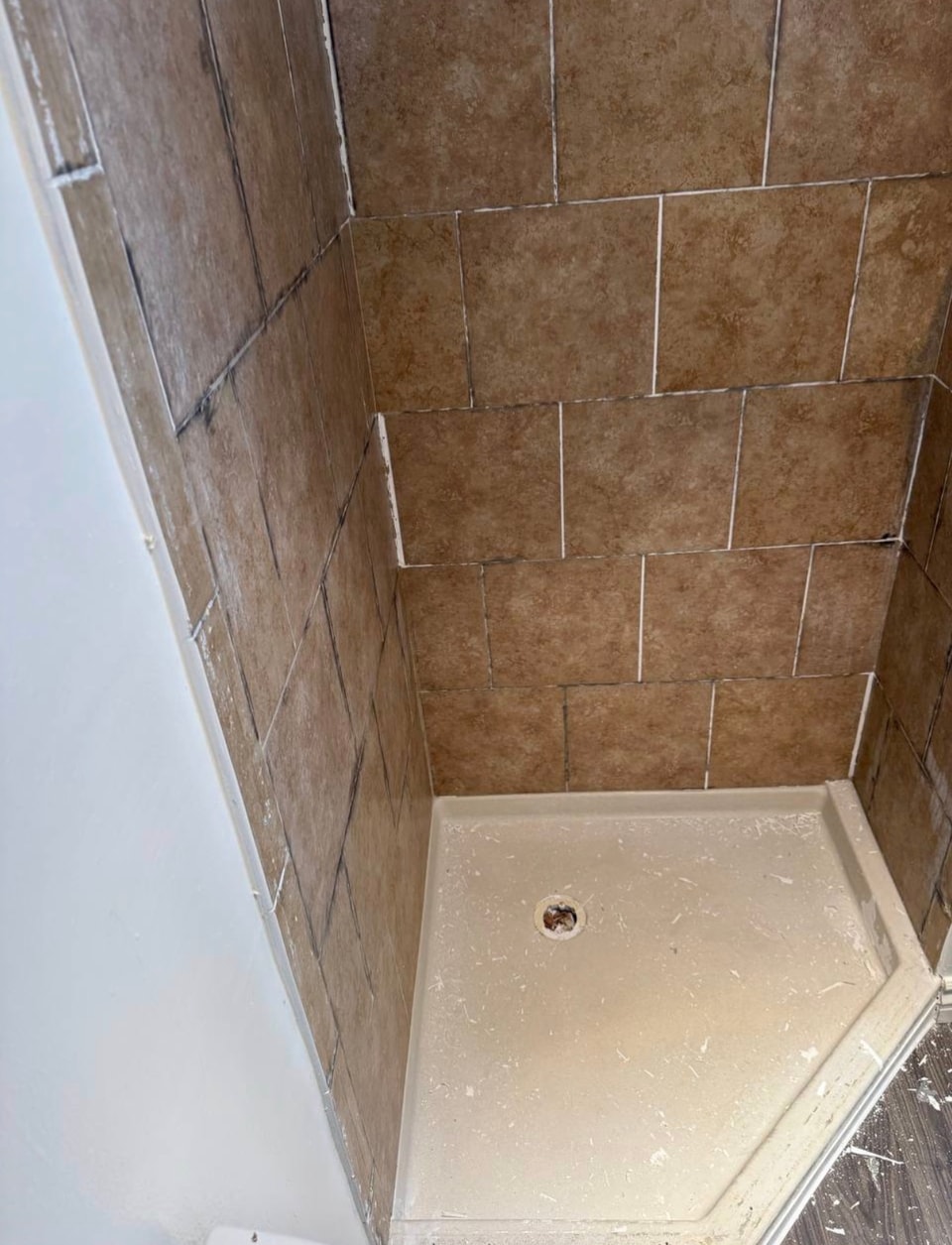 Brown shower wall tile with visible discoloration before reglazing