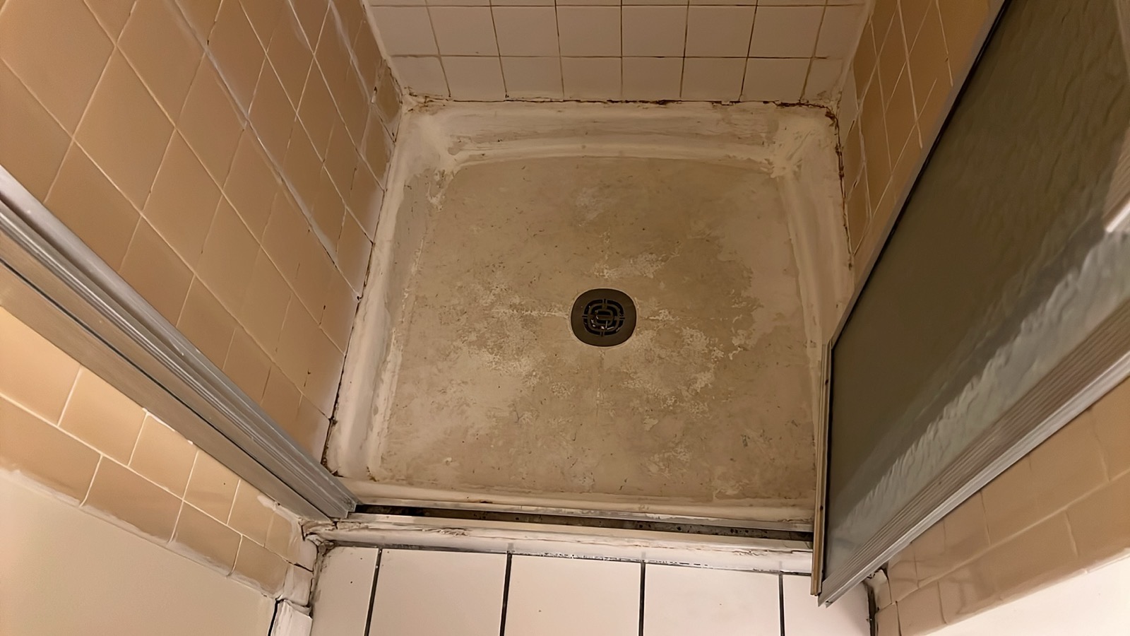 Damaged shower base with stains, cracks and deterioration before restoration in Los Angeles home
